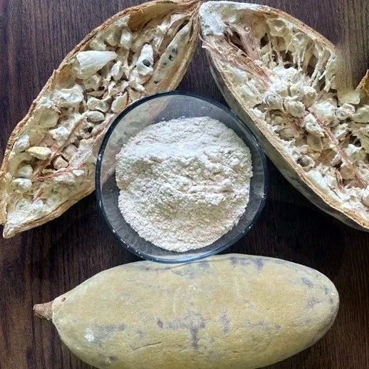Baobab fruit powder in a glass bowl beside split baobab pods